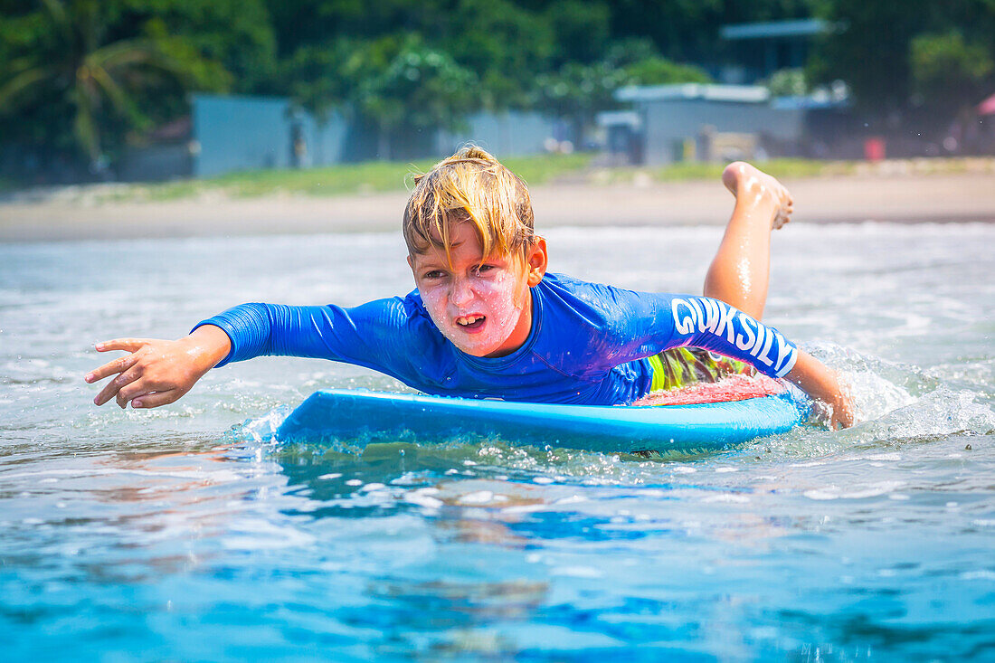 Young surfer, happy young boy in the ocean on surfboard