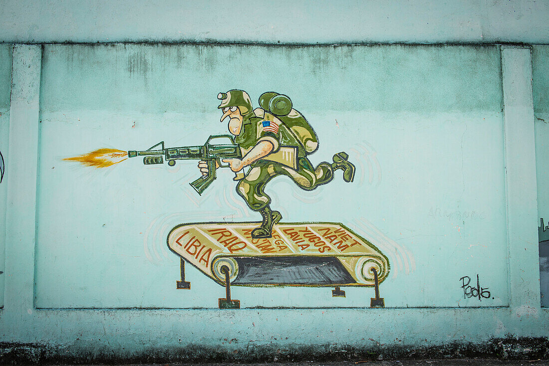 'A hand-painted Cuban wall mural depicts a US soldier shooting an automatic weapon while running on a treadmill marked Vietnam - Yugoslavia - Afganistan - Iraq - Libia''. An Anti-war and anti-US cartoon painted on the wall of a shop in Santa Clara, Villa 