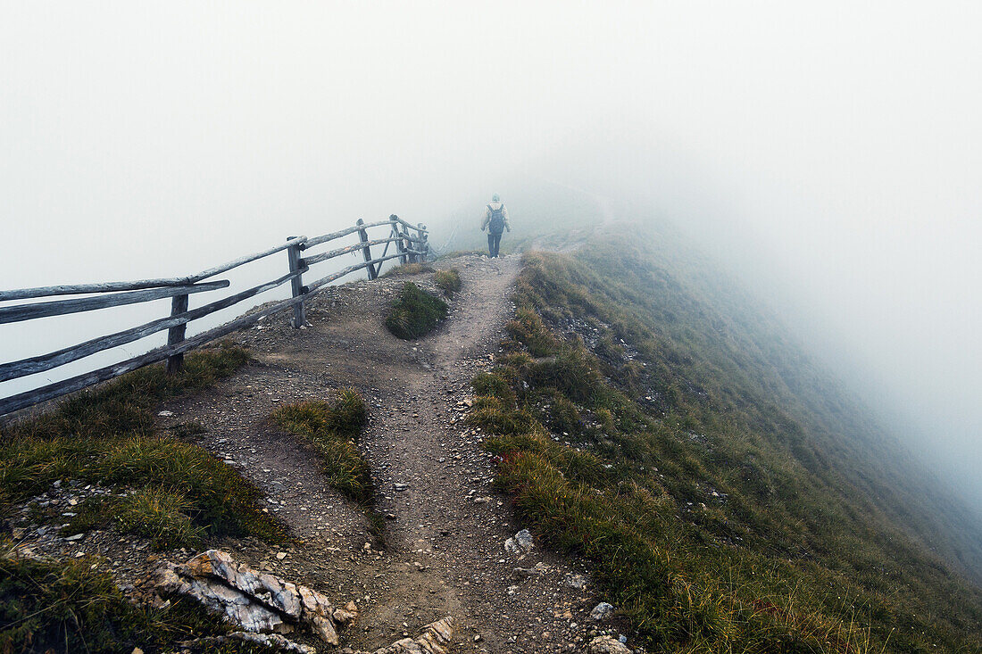Hiker surrounded by thick fog, Puez-Geisler Nature Park, Dolomites, Unesco world heritage, South Tyrol, Italy