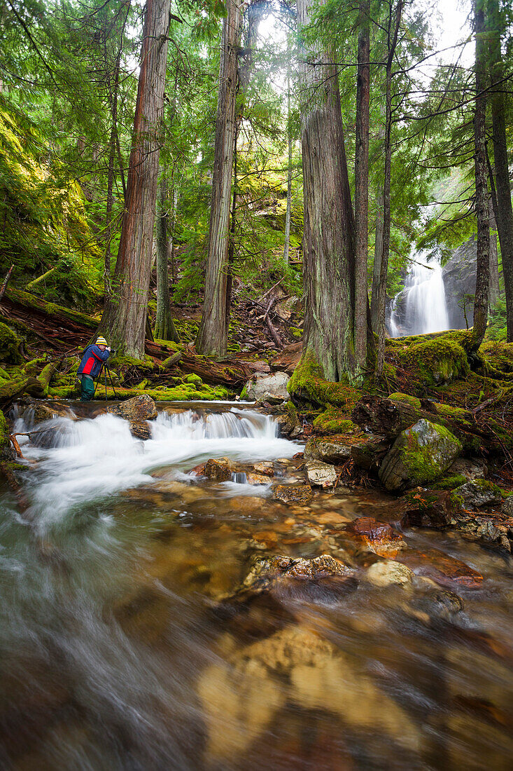 A photographer takes a picture of Cedar Hollow Falls in North Cascades National Park, Washington.