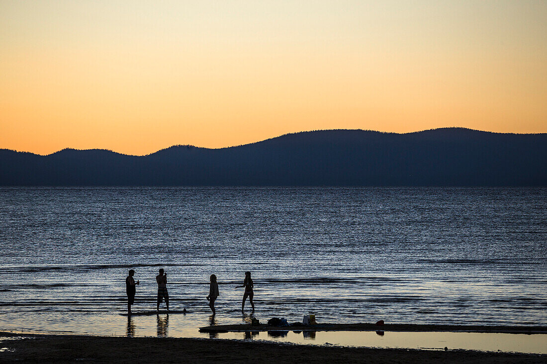 Friends hanging out along El Dorado beach in South Lake Tahoe at sunset.