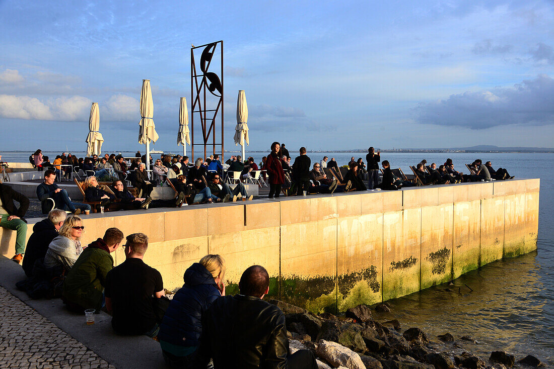People sitting on the banks of the river Tejo at Cais do Sodre, Lisbon, Portugal