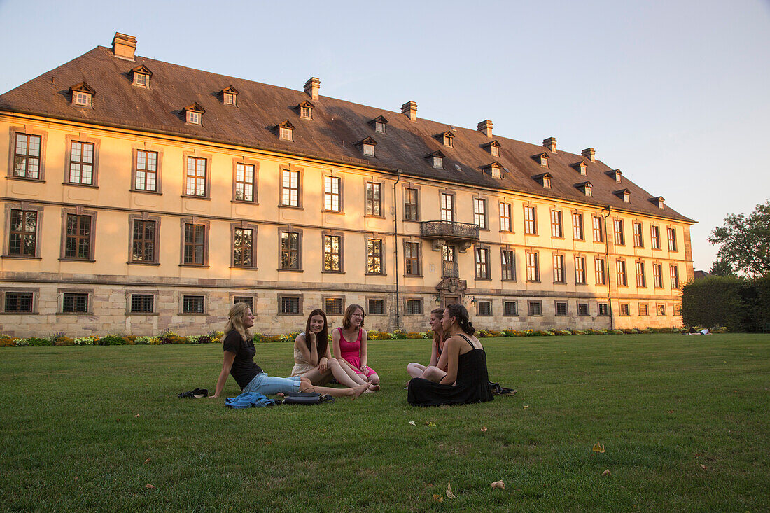 Fünf junge Frauen sitzen auf dem Rasen vom Schlossgarten vor dem Stadtschloss, Fulda, Rhön, Hessen, Deutschland