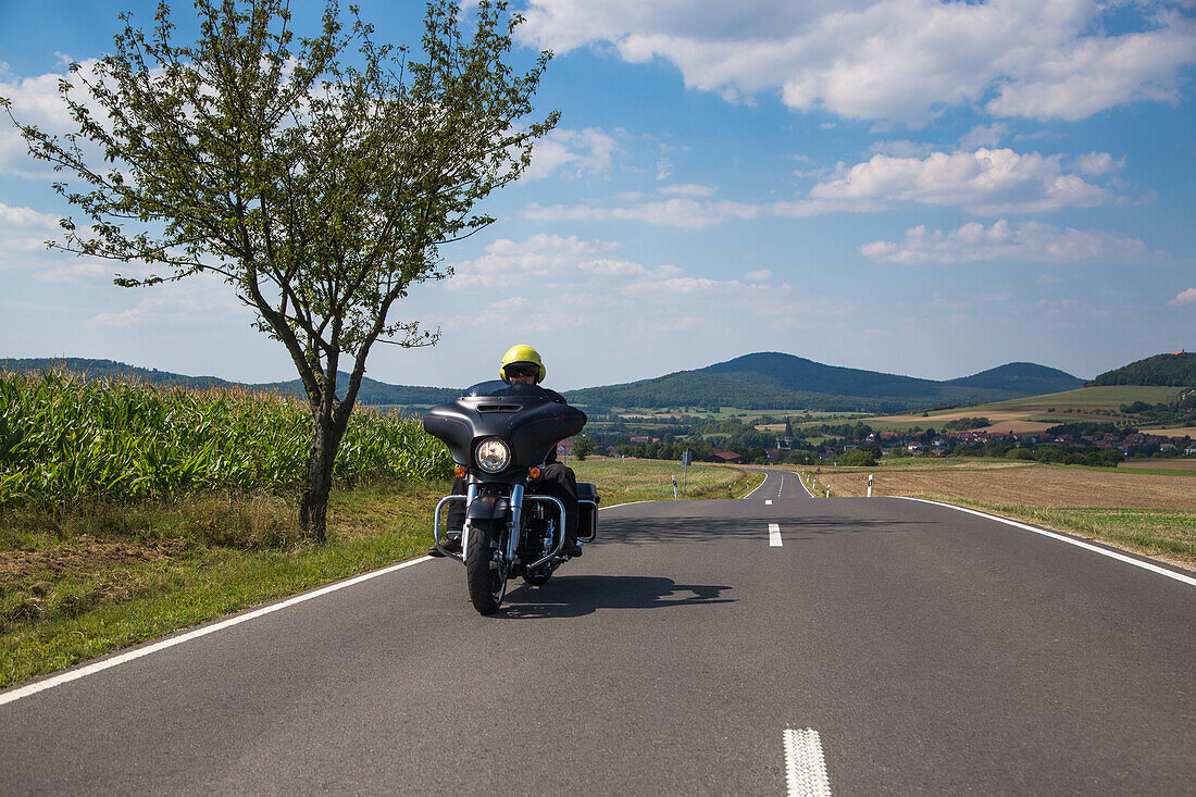 Motorradfahrer auf einer Harley-Davidson auf der Straße zur Gedenkstätte Point Alpha mit Hessischen Kegelspiel im Hintergrund, nahe Rasdorf, Rhön, Hessen, Deutschland