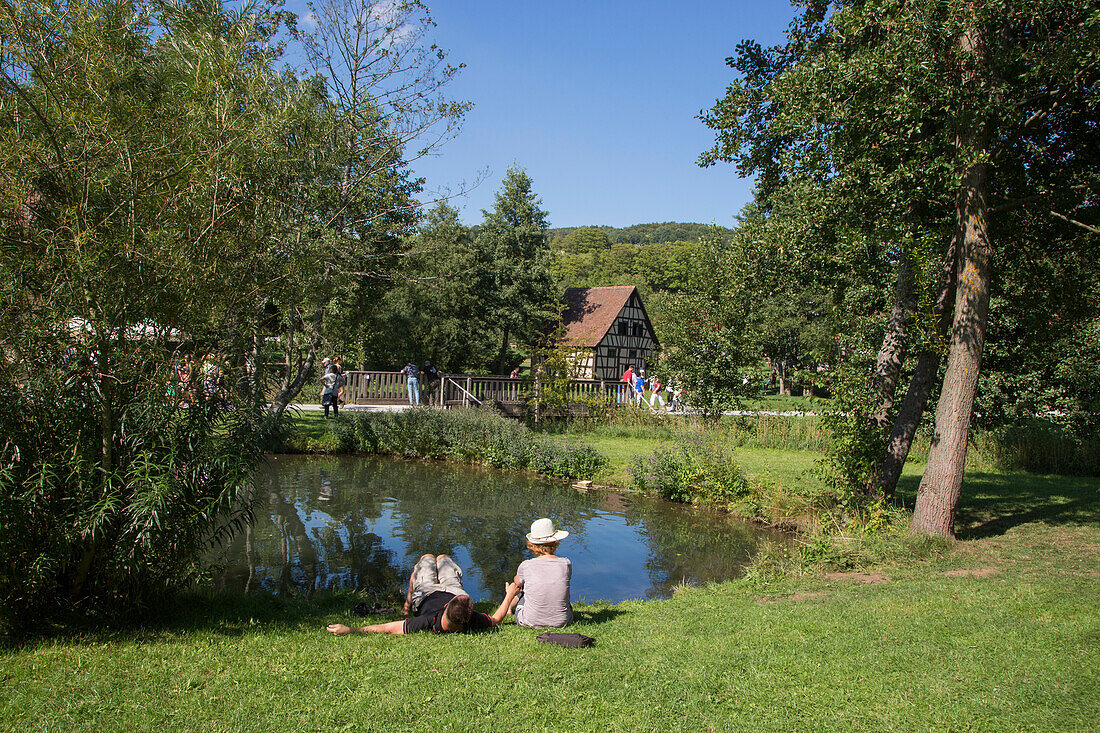 Menschen entspannen sich am Teich von Fränkisches Freiluftmuseum Fladungen, Fladungen, Rhön, Bayern, Deutschland