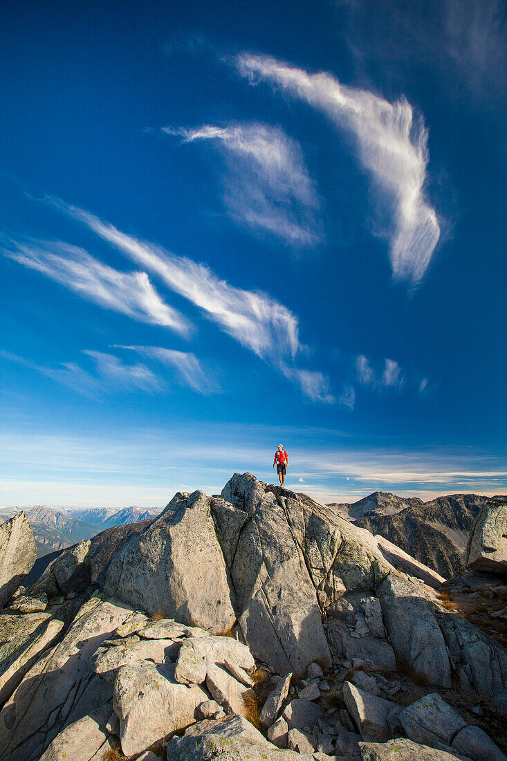 A backpacker stands on top of a rocky summit near Whistler, British Columbia, Canada.