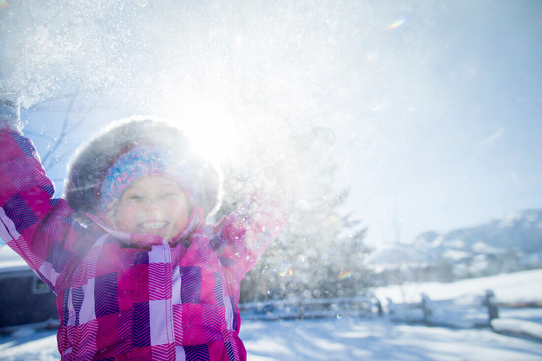 Young girls smiling and playing in the snow on a beautiful winter day.