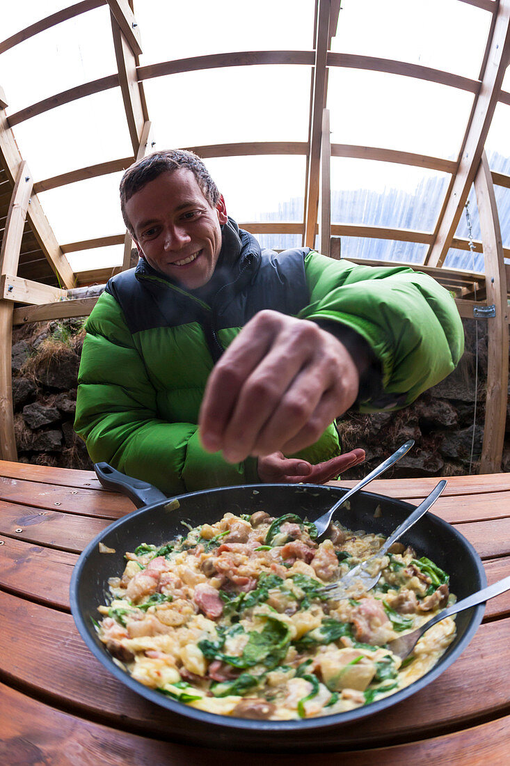 Man cooking a stew in a shelter, made by climbers, located at Hnappavellir climbing area, southeast Iceland.
