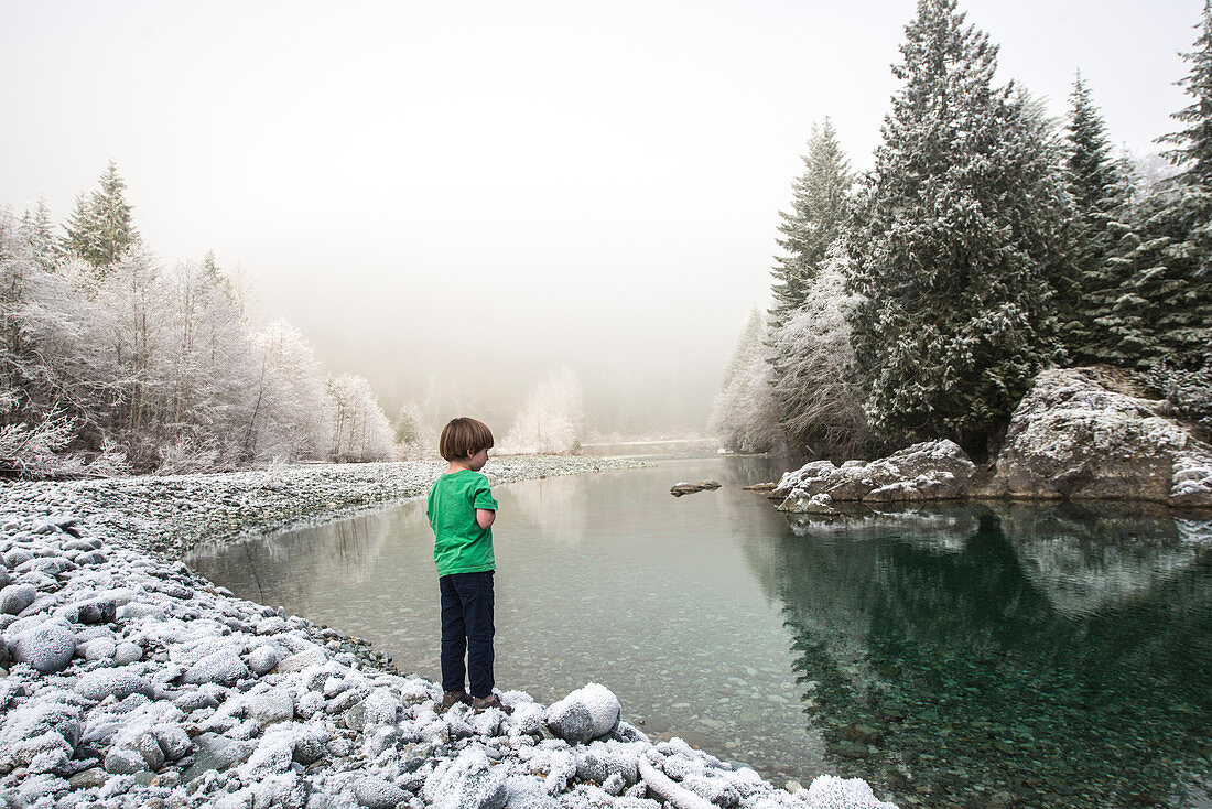 A young boy stands on the bank of the Taylor River on the road to Tofino, British Columbia.