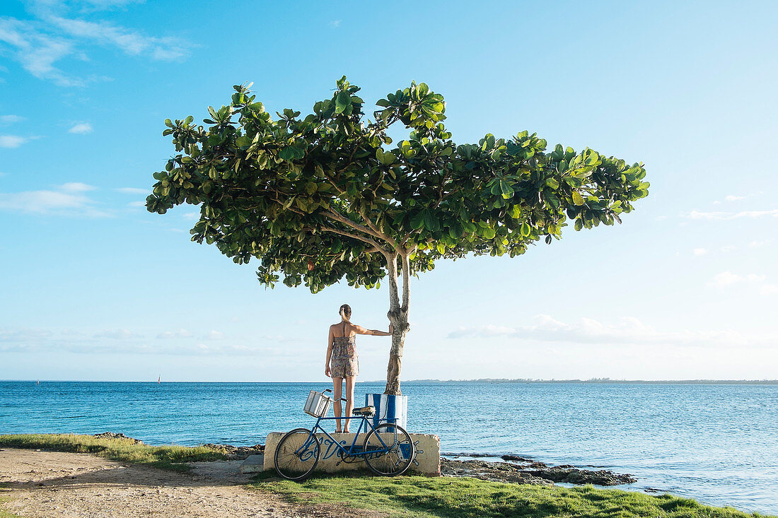 A girl stands next to a tree in Playa Larga, Cuba