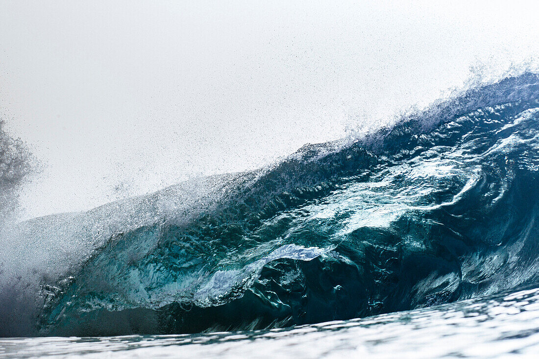 An empty wave breaks over a shallow reef