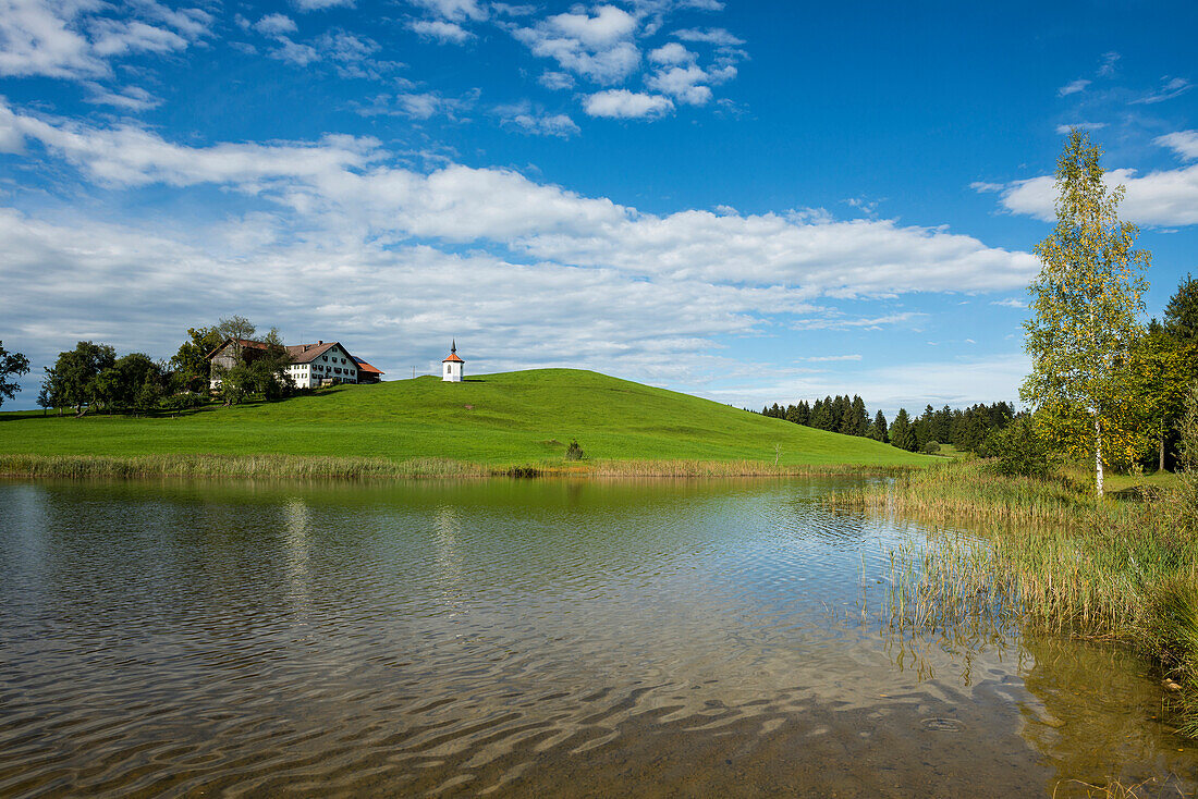 Hegratsrieder See, with traditional farmhouse and chapel, near Füssen, Bavaria, Germany