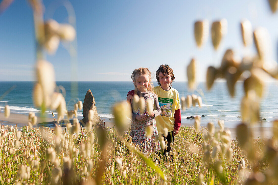 Children standing in wildlowers growing near beach