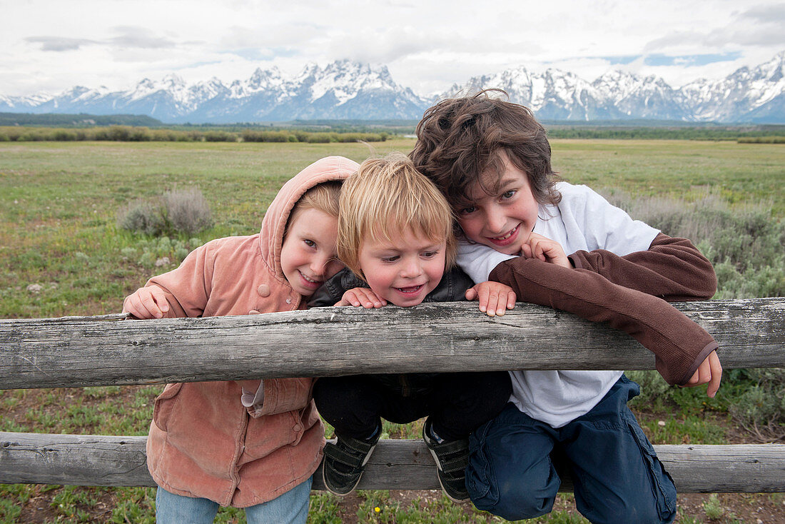 Children leaning against fence in Grand Teton National Park, Wyoming, USA