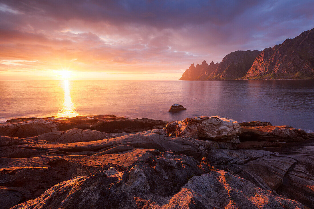 Beeindruckender Sonnenuntergang über den Felsen Okshornan am Ersfjordr in Nordnorwegen, Insel Senja, Fylke Troms, Norwegen, Skandinavien