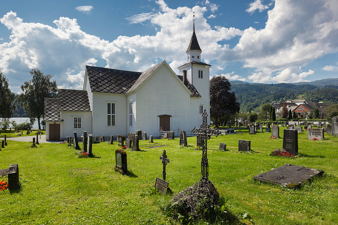 Kirche von Ulvik mit blauem Himmel, Blumen und Gräbern im Sommer, Hardangerfjord, Hordaland, Norwegen, Skandinavien