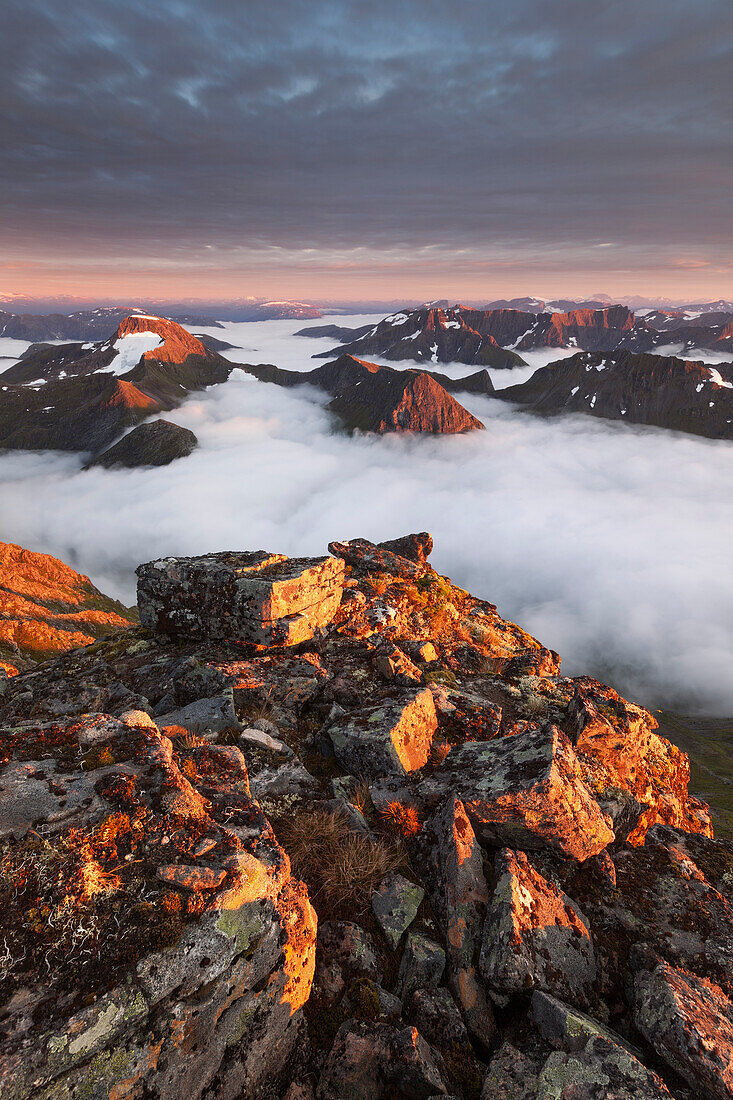 Blick vom Gipfel des Skårasalen auf die umliegenden Gipfel und die wolkenverhangenen Täler der Sunnmøre Alpen im letzten Abendlicht, Ålesund, Fylke Møre og Romsdal, Norwegen, Skandinavien