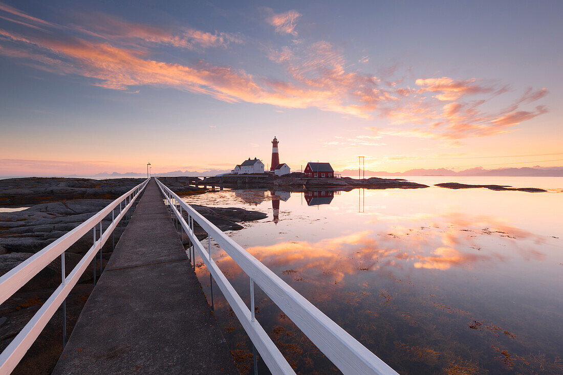 Romantic sunset above the lighthouse Tranøy Fyr on the coast of the Vest Fjord with the Lofoten wall in the background and a stage in the foreground, Tranøya, Hamarøy, Nordland, Norway, Scandinavia