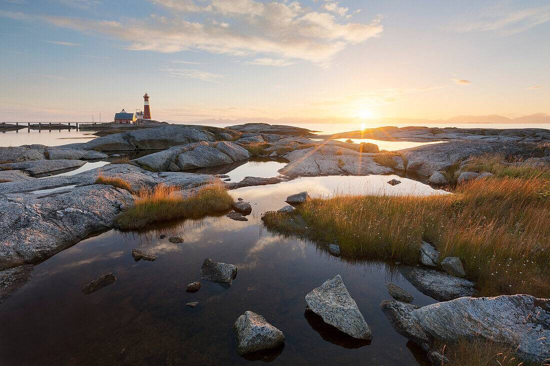 Romantischer Sonnenuntergang am Leuchtturm Tranøy Fyr an der Küste des Vestfjord mit kleinen Seen im Vordergrund, Tranøya, Hamarøy, Nordland, Norwegen, Skandinavien