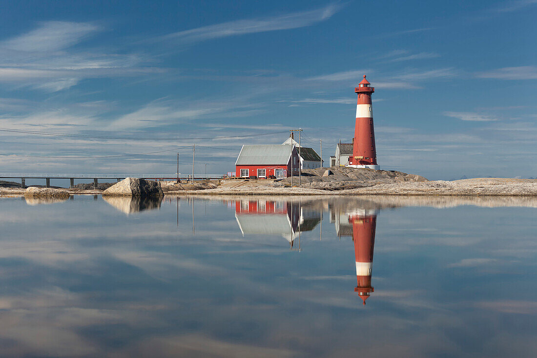 Der rote Leuchtturm Tranøy Fyr an einem sonnigen Sommertag mit Spiegelung im Meer, Tranøya, Hamarøy, Nordland, Norwegen, Skandinavien