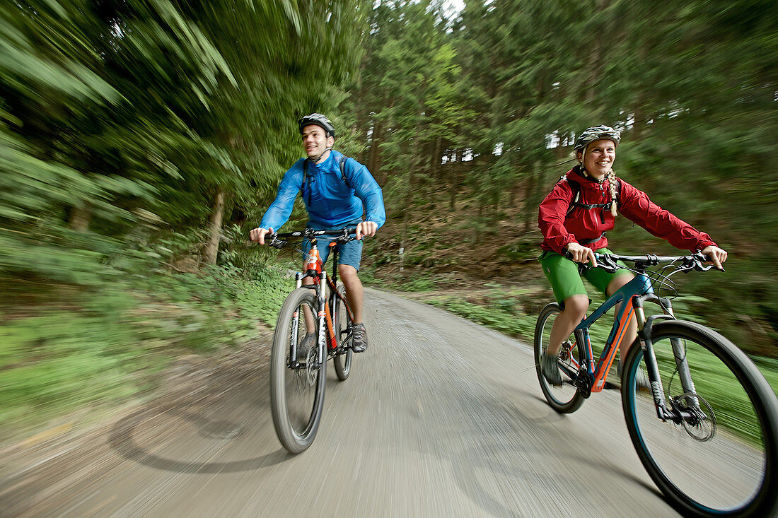 Cyclists riding down a path in a forest