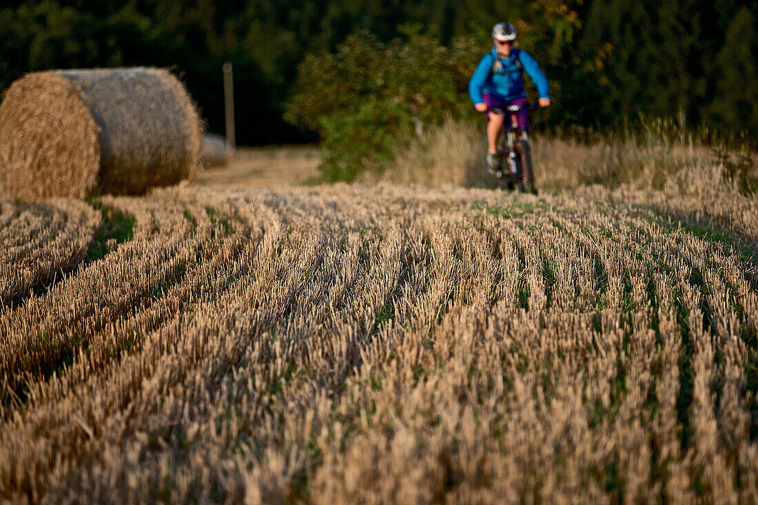 Junge Frau fährt Fahrrad durch ein Feld