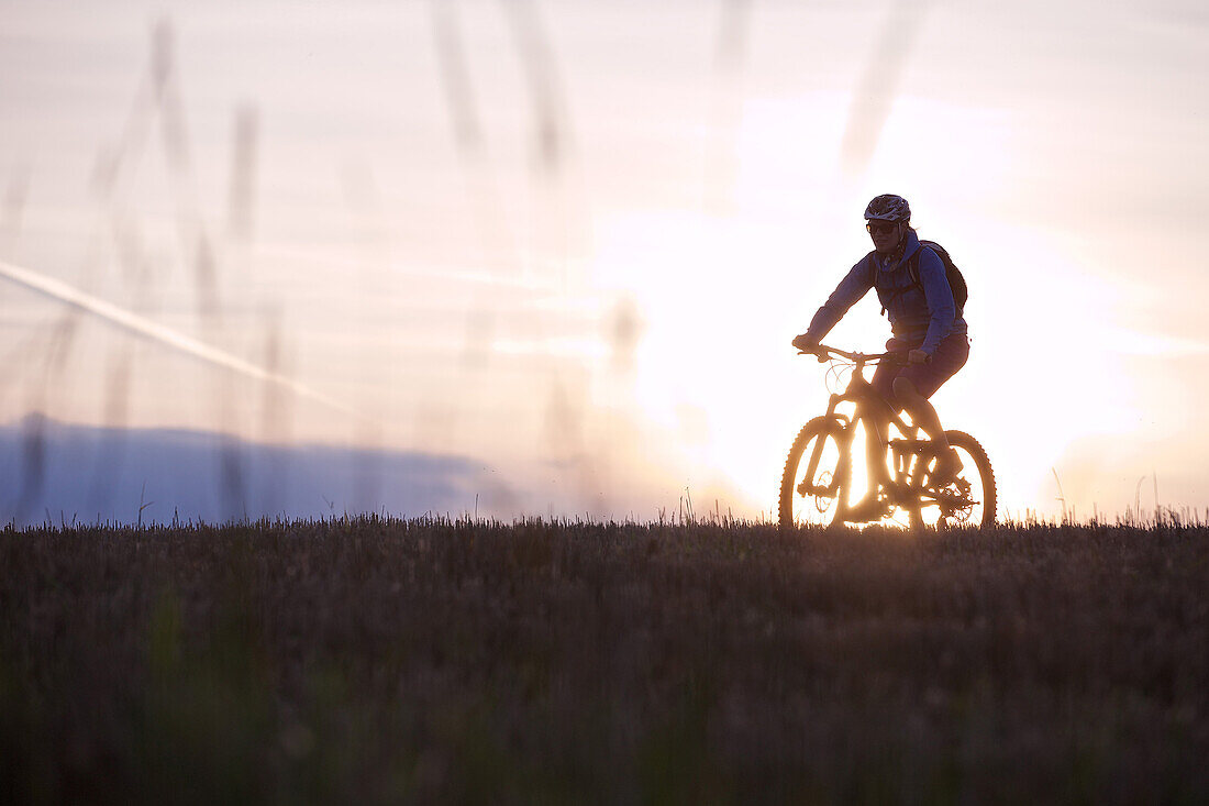 Young woman riding with her bike through a field