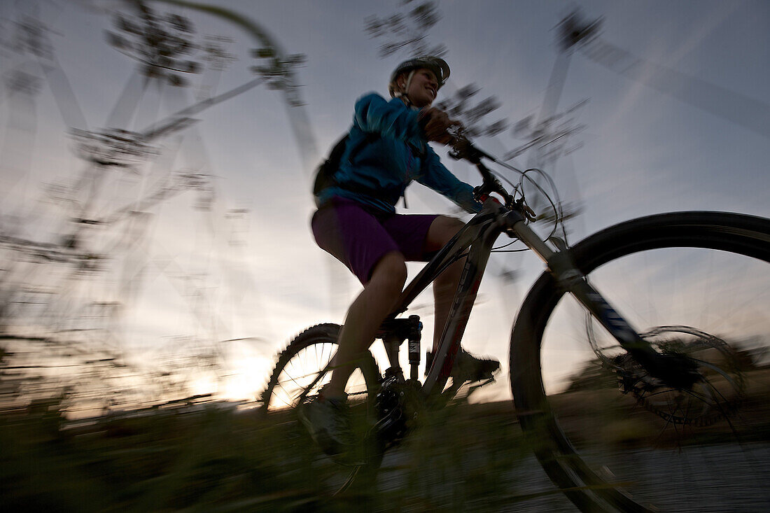 Young woman riding with her bike on a way between fields