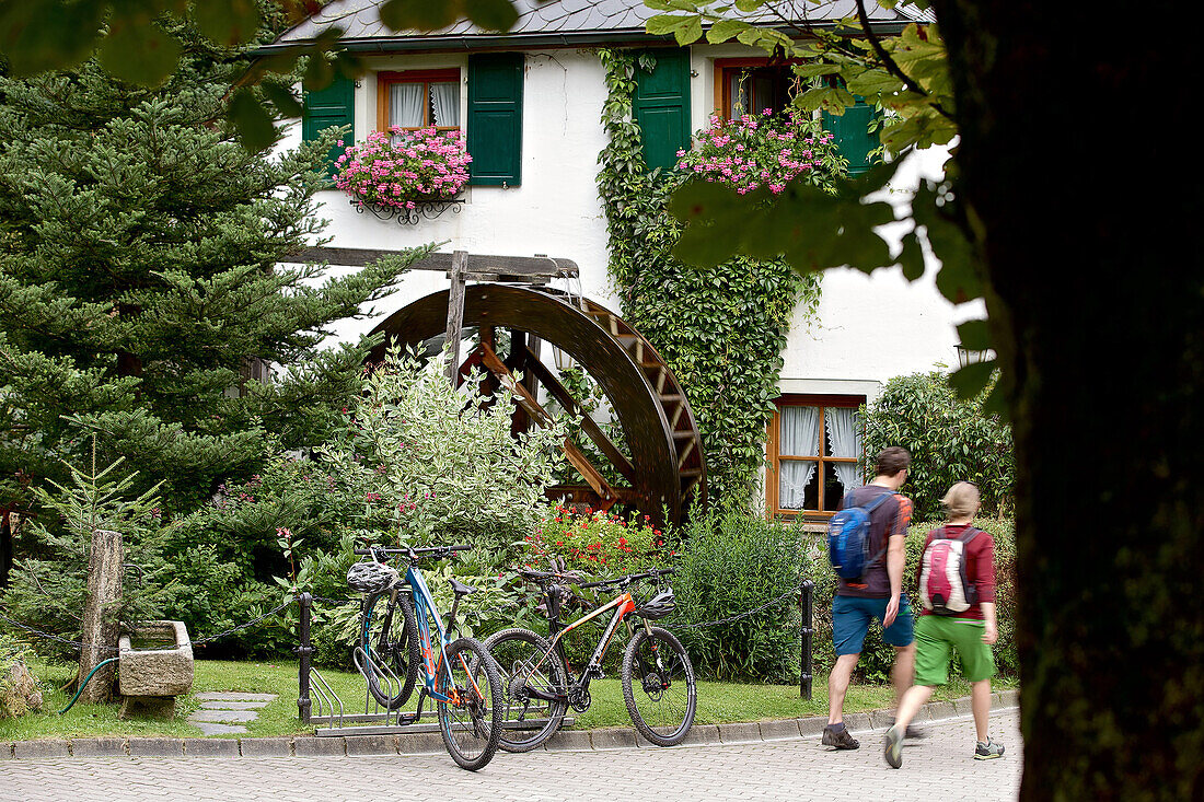 Zwei Fahrradfahrer laufen zu einem Wirtshaus