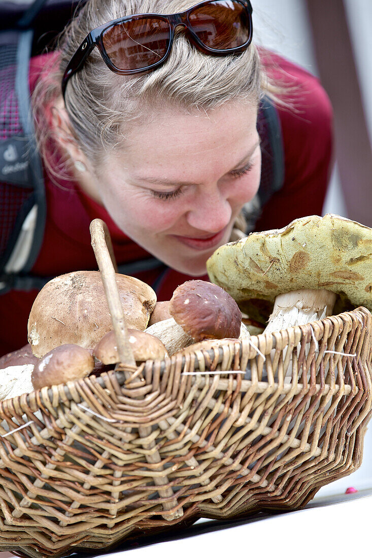 Young woman smelling at a basket full of mushrooms
