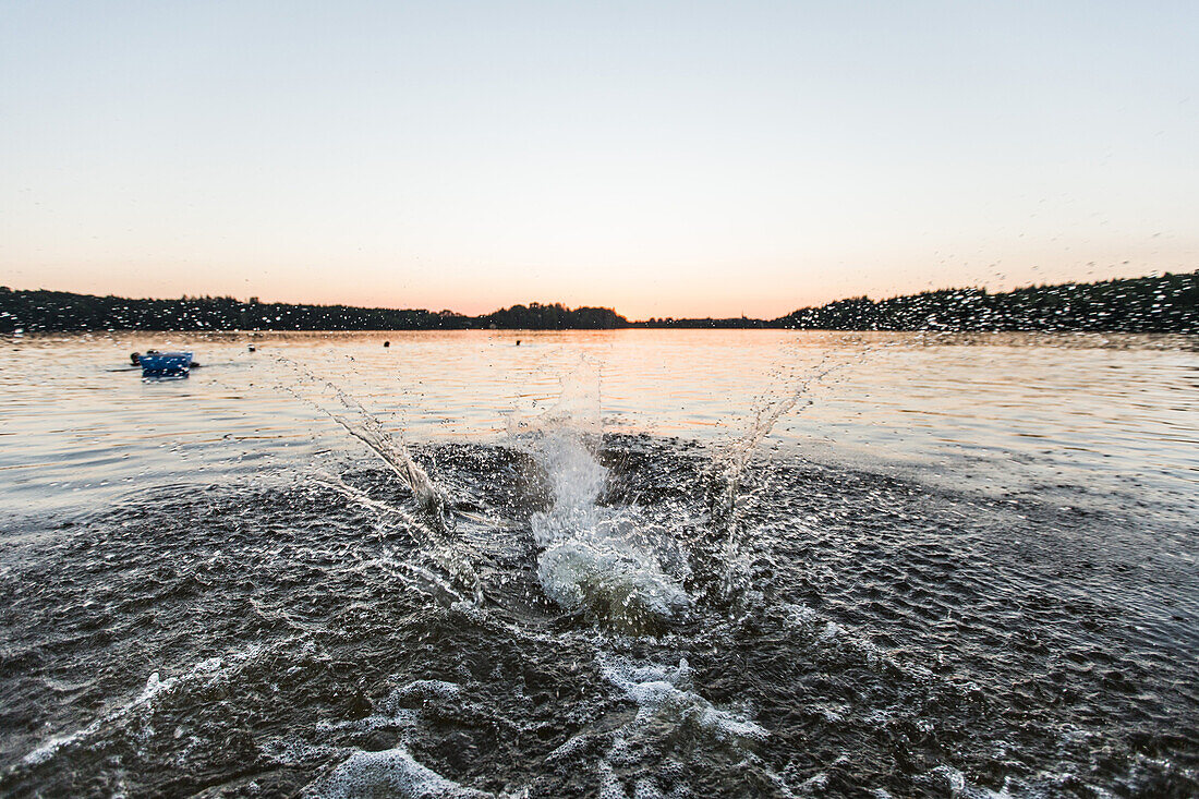 Young man jumping into the water of a lake, Freilassing, Bavaria, Germany