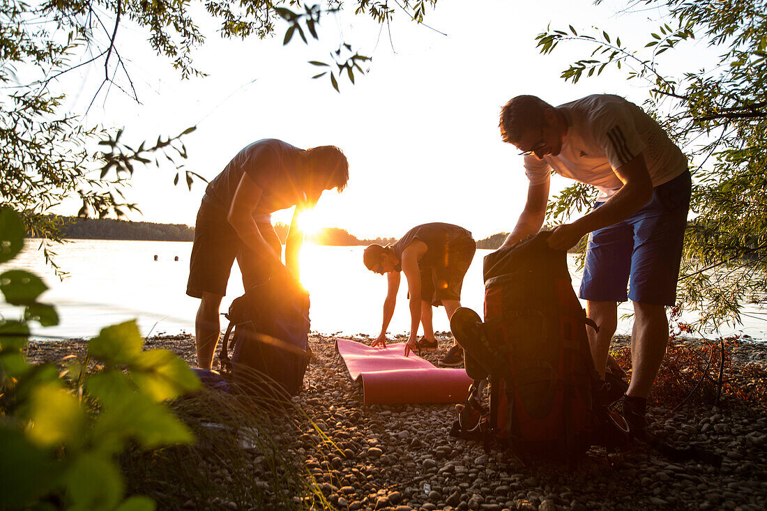 Drei junge Camper bereiten ihre Sachen vor an einem See, Freilassing, Bayern, Deutschland