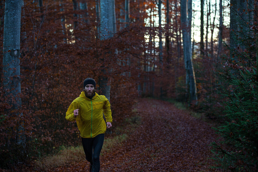 Junger Mann läuft auf einem Weg durch einen Wald, Allgäu, Bayern, Deutschland