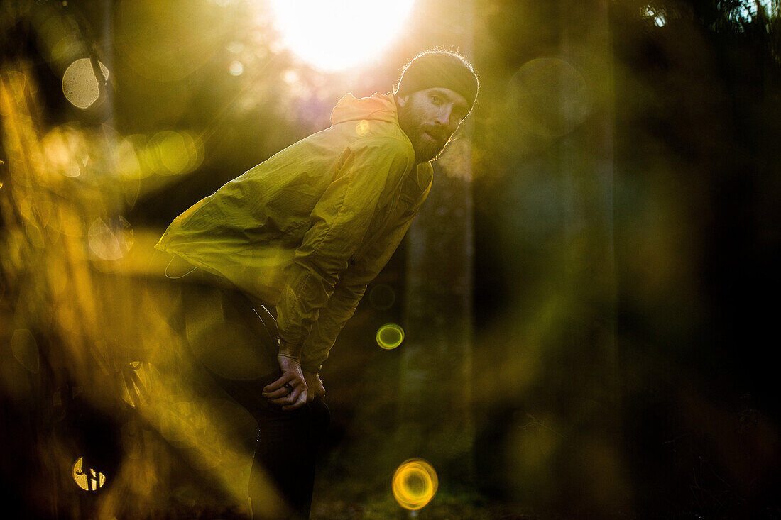 Young male runner having a short break in a forest, Allgaeu, Bavaria, Germany