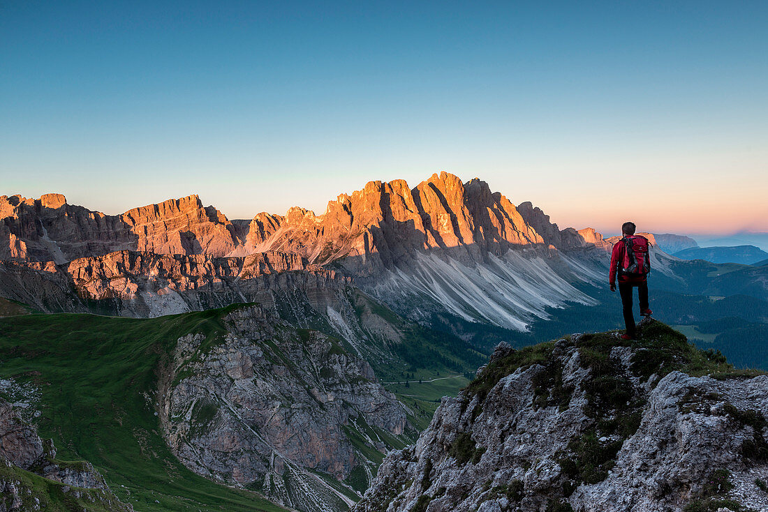 Odle di Eores, Dolomites, South Tyrol, Italy. Hiker admires the sunrise on the Odle