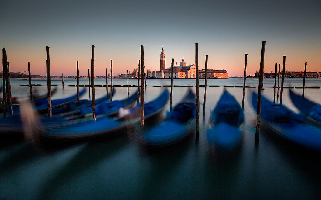 Venice, Veneto, Italy. View of San Giorgio cathedral during a quiet winter sunset, with gondolas on the foreground.