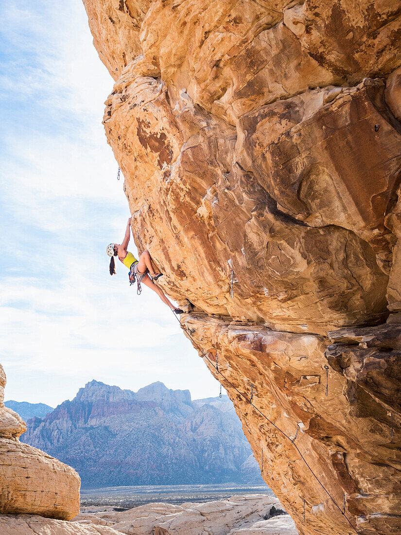 Mixed race girl rock climbing on cliff