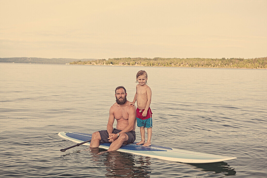 Caucasian father and son on paddleboard in lake