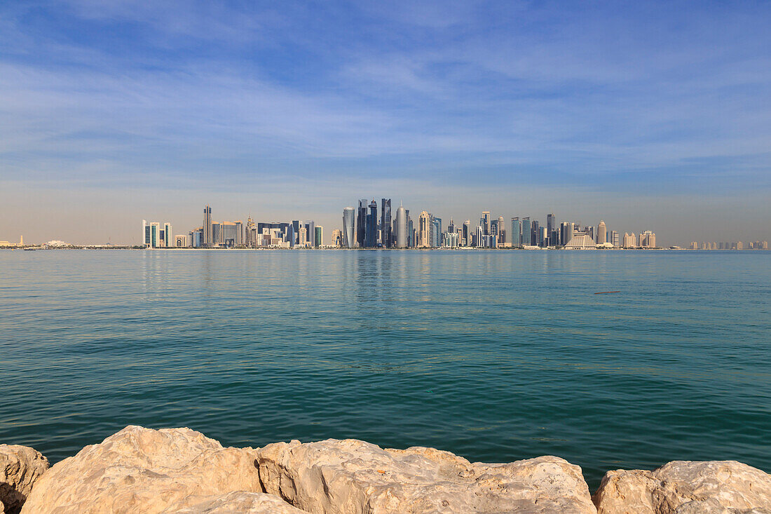 Modern city skyline of West Bay, across the calm turquoise waters of Doha Bay, from the Dhow Harbour, Doha, Qatar, Middle East