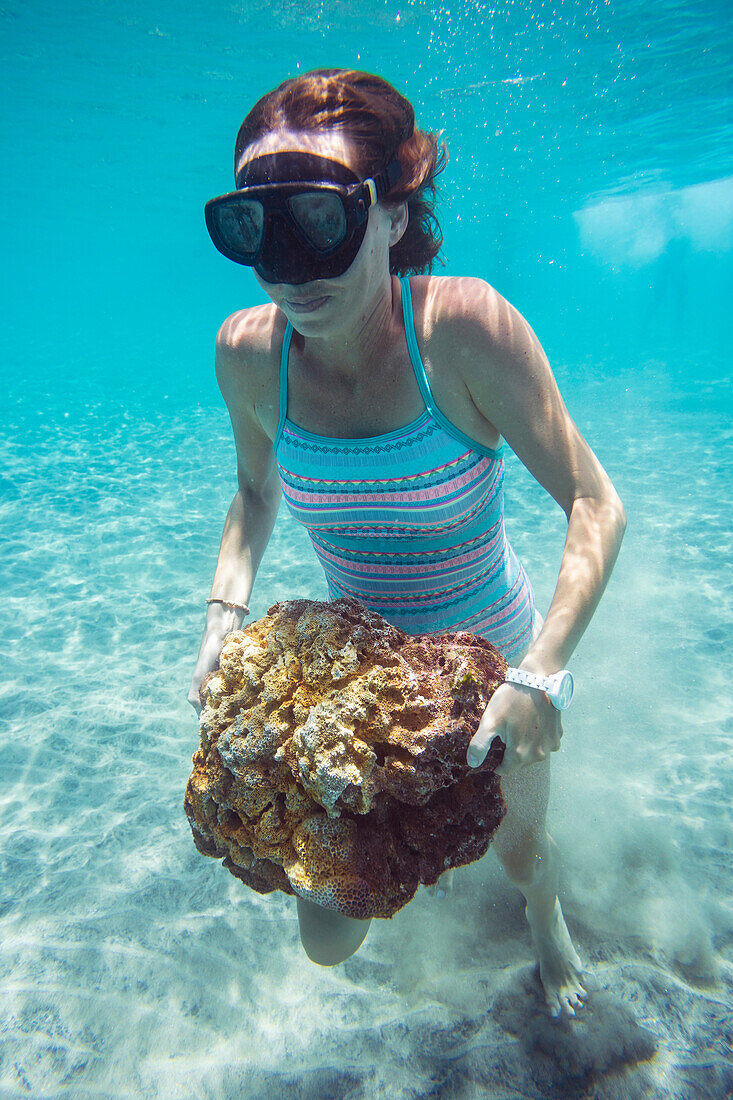 Young woman walking with stone underwater.