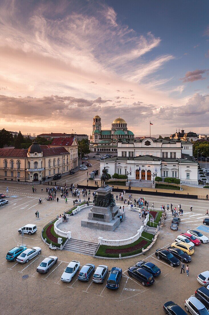 Bulgaria, Sofia, Ploshtad Narodno Sabranie Square, Statue of Russian Tsar Alexander II, National Assembly building, and Alexander Nevski Cathedral, elevated view, dusk.