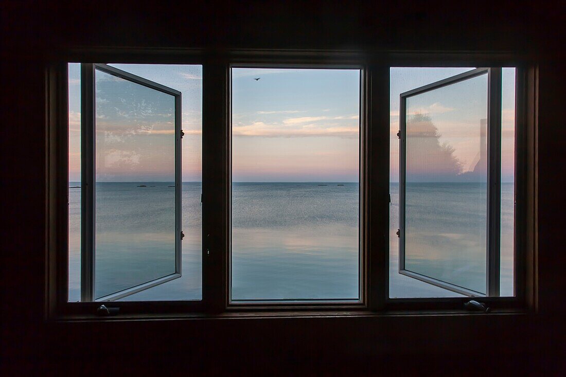 View of the Atlantic Ocean from an upstairs bedroom 3 unit picture window of a large home in Connecticut, overlooking the ocean at dawn.