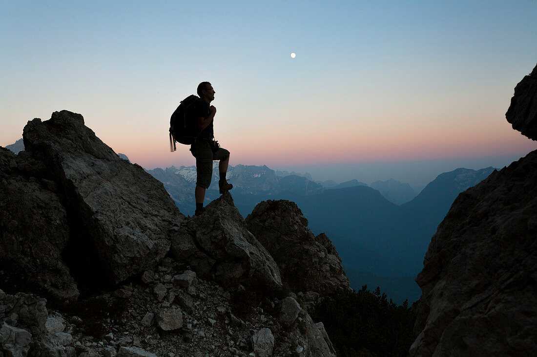 Europe, Italy, Veneto, Belluno, Dolomites. Silhouette of hiker in mountain at dusk