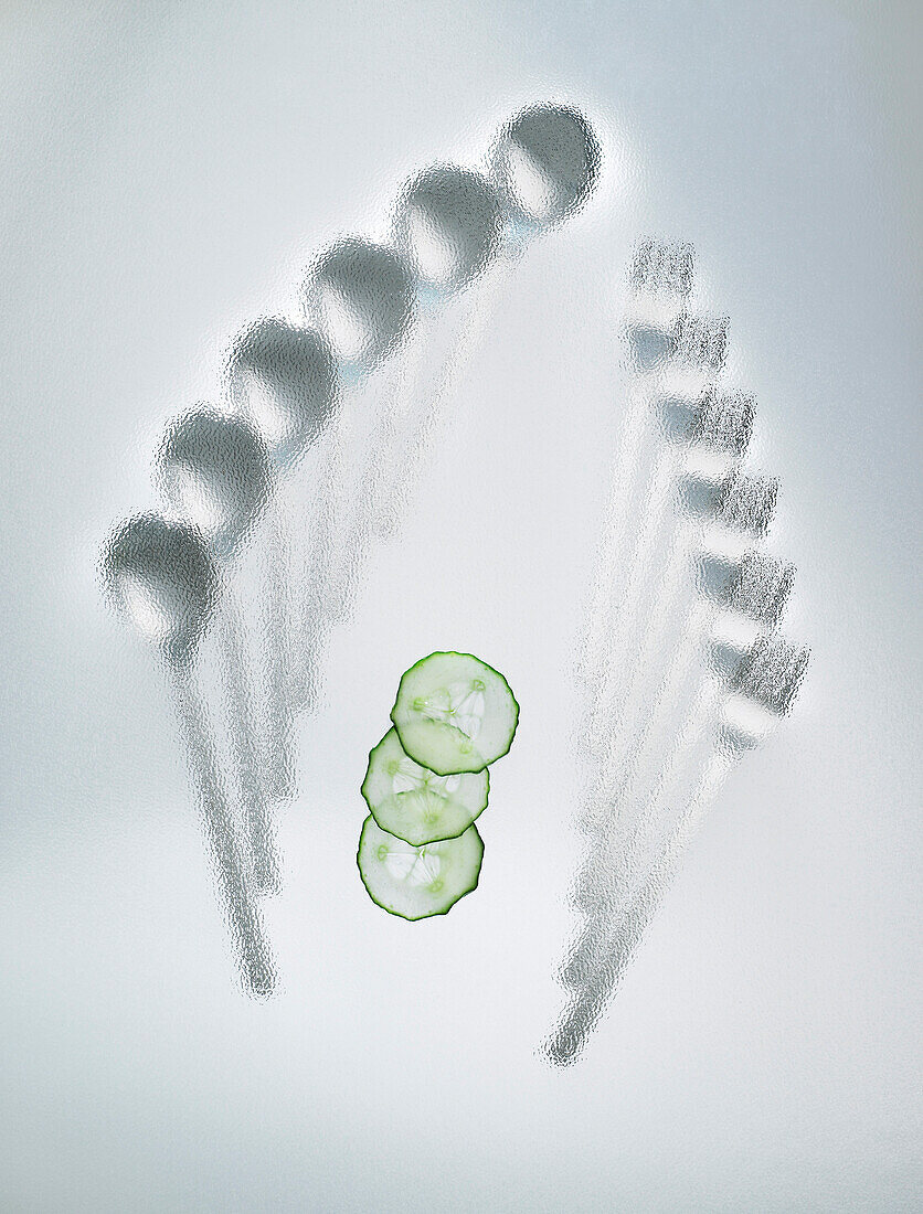 Cutlery under glass with slices of cucumbers