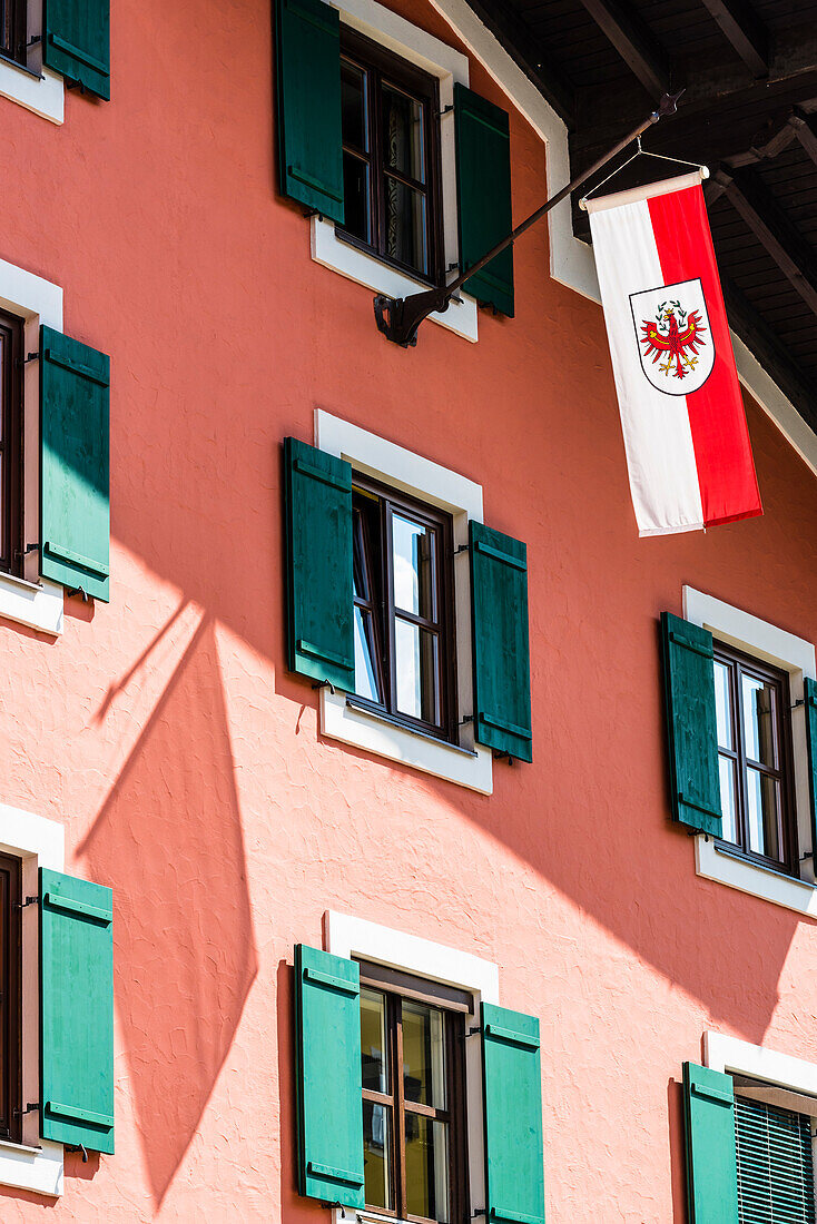 Die Tiroler Landesflagge an einem Stadthaus mit Fensterläden in der Altstadt, Kitzbühel, Tirol, Österreich