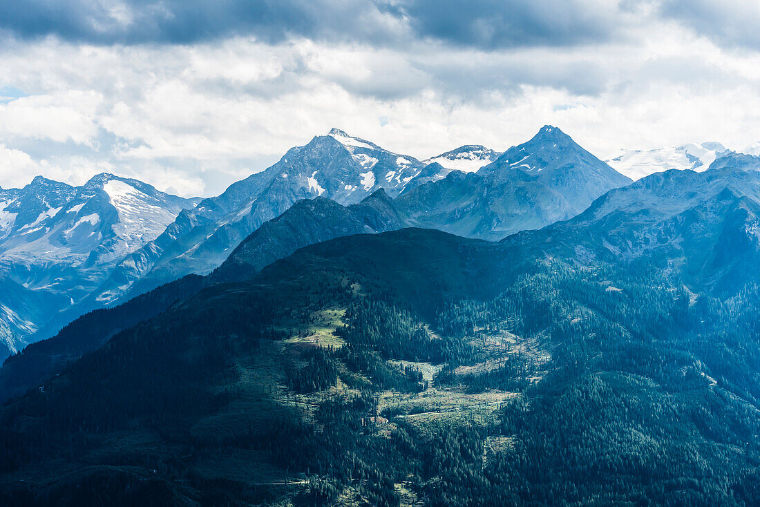 Ein Berghang im Sonnenlicht mit Gebirgskulisse, Kitzbüheler Alpen, Kitzbühel, Tirol, Österreich