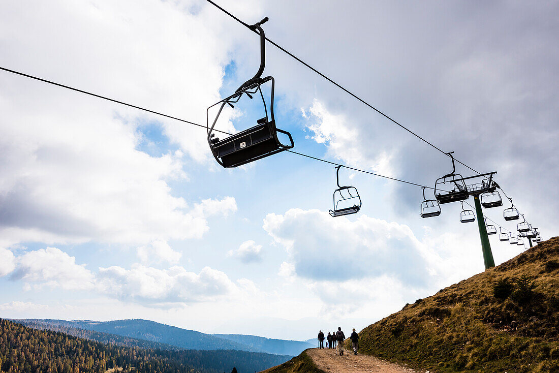 Hiker in the off season on a panoramic trail in the Sarntaler Alps and an inactive chairlift, Merano, South Tirol, Alto Adige, Italy