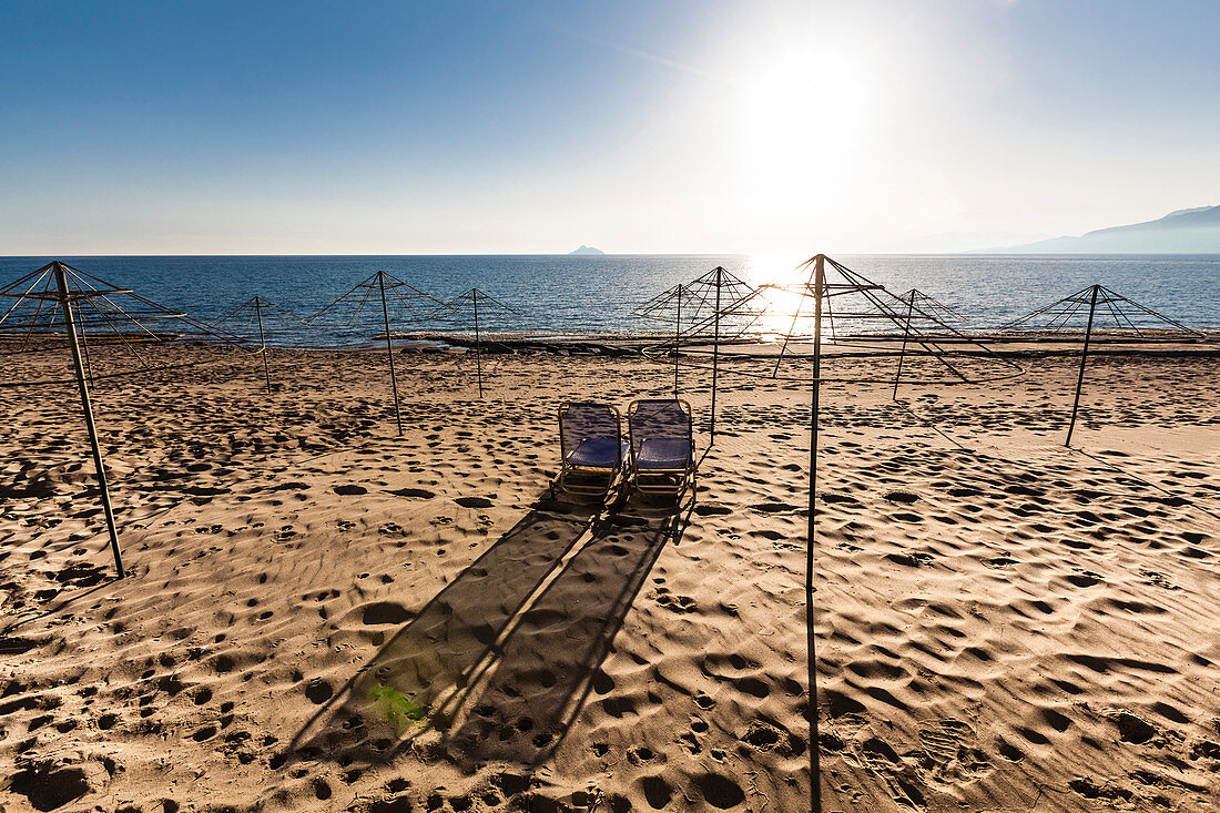 Einsamer Strand mit Gerippen für Sonnenschirme und 2 Liegestühle und Blick auf das Mittelmeer, Kalamaki, Kreta, Griechenland