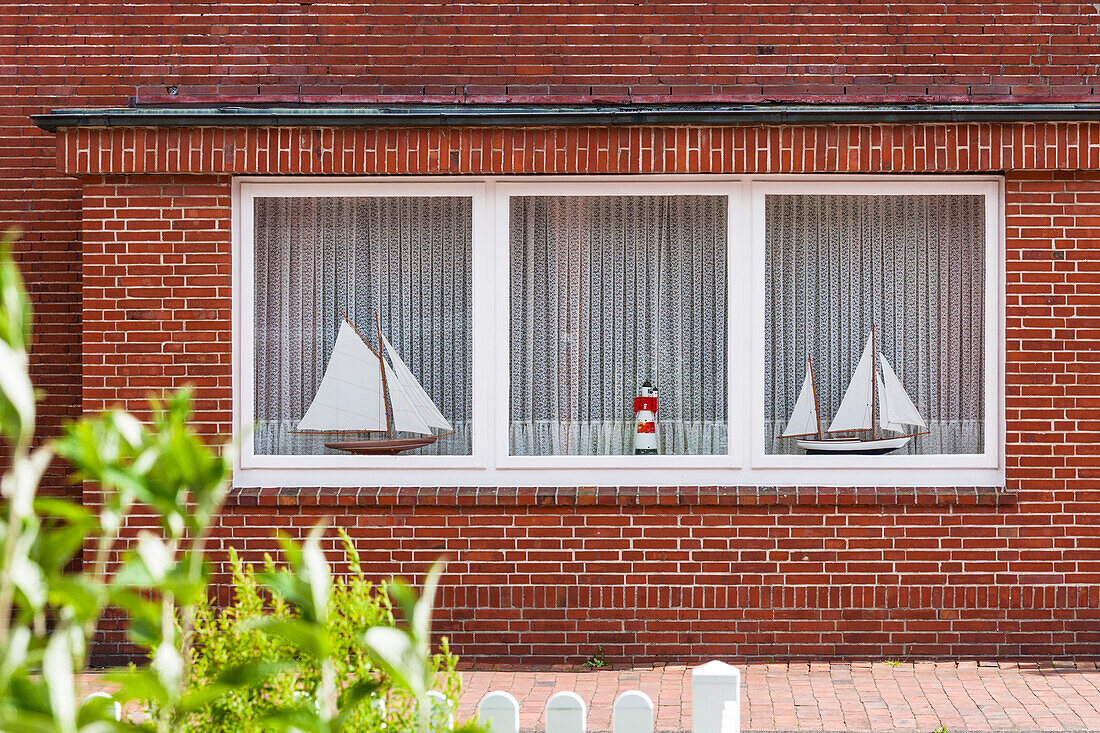 Two sailing ships and a lighthouse as models in the window of a typical Frisian brick building, Juist, Schleswig Holstein, Germany