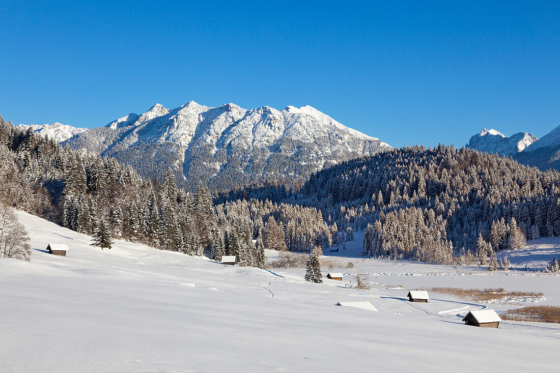 Winterlandschaft mit Heustadeln am Geroldsee, Blick zur Soierngruppe, Bayern, Deutschland